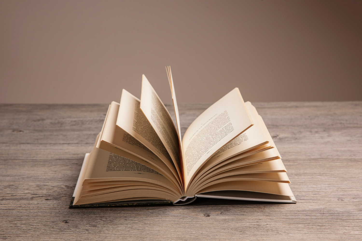 Un livre ouvert est posé sur une table en bois.